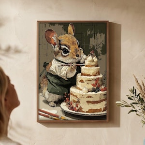 Könnte beinhalten: Gerahmter Kunstdruck, der ein Eichhörnchen in Kochkleidung beim Dekorieren einer mehrstöckigen Torte zeigt. Die Torte ist mit Beeren und Sahne verziert. Der Druck hängt an einer Wand über einem Holzschrank.