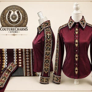 Könnte beinhalten: Burgunderfarbenes Reitturniershirt mit aufwendigen gold-schwarzen Verzierungen an Kragen, Manschetten und Ärmeln. Ein passendes Sattelpad und ein Gürtel ergänzen das Ensemble. Das Couture Charms Store Logo ist sichtbar.