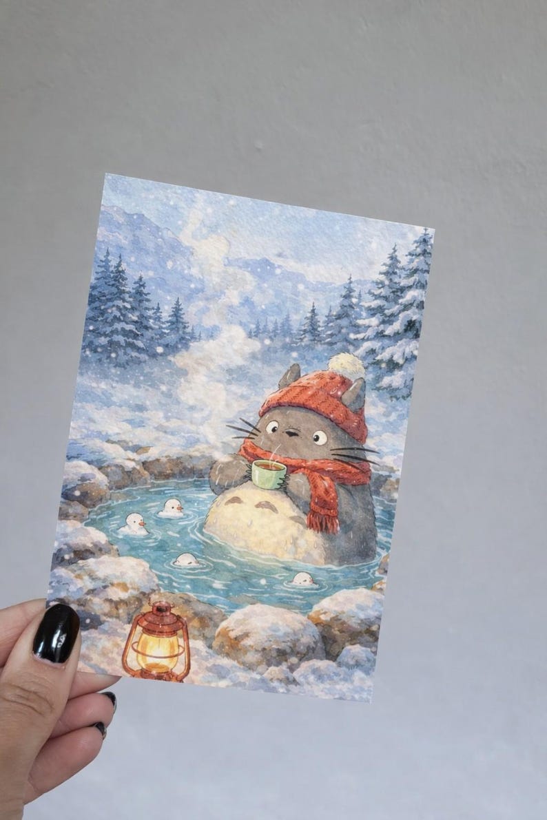 May include: Watercolor illustration of a gray cat-like creature wearing a red hat and scarf, enjoying a hot spring in a snowy landscape. The creature holds a cup, surrounded by small white spirits. A lantern glows nearby.