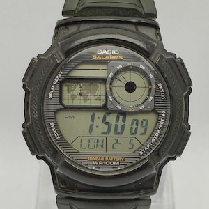 Puede incluir: Reloj digital Casio negro con correa verde. La esfera muestra la hora, la fecha y un mapa del mundo. Funciones: split-reset, alarmas y batería de 10 años. Resistente al agua hasta 100 metros.