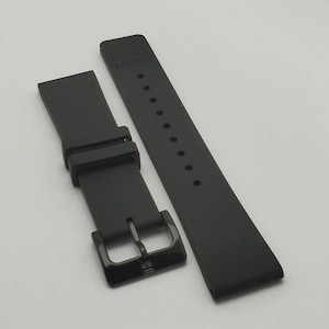 May include: Black watch strap with a matte finish. The strap has a buckle closure and a series of holes for adjustment. The strap is made of a flexible material and is designed to fit a watch. The brand name is printed on the strap.