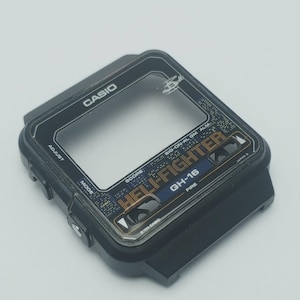 May include: Black Casio watch face with the text "HELI FIGHTER" and "GH-16". The watch face has a clear screen and the Casio logo at the top. The watch face has the text "ADJUST" and "MODE".