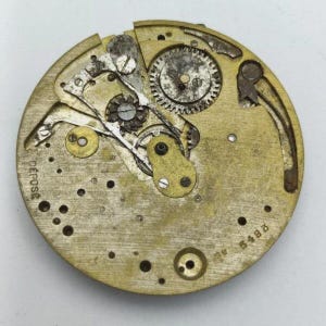 May include: A vintage watch movement with intricate gears and mechanisms. The circular brass plate features the word "DEPOSE" and the number "6488". The internal components include various wheels, levers, and screws, showcasing the detailed craftsmanship of the timepiece.