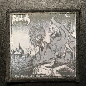 May include: A square fabric patch with a black stitched border featuring a grayscale illustration of a grim reaper figure standing over a fallen person in a graveyard. The text Sabbat is printed in the top left and for Satan And Sacrifice below.