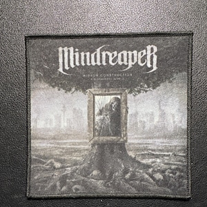 Könnte beinhalten: Ein schwarz-weißer Aufnäher mit dem Bandnamen "Mindreaper" in gotischer Schrift. Der Aufnäher zeigt eine surreale Szene mit einer Figur in einem Fenster, einem Baum und einer Stadtlandschaft. Der Text "Mirror Construction" und "A Crumbling World" ist ebenfalls sichtbar.