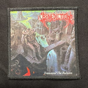 Puede incluir: Parche cuadrado con una ilustración detallada de fantasía. El parche presenta la palabra "BENEDICTION" en letras rojas estilizadas. Debajo de la ilustración está el texto "Transcend The Rubicon". El parche tiene un borde negro.
