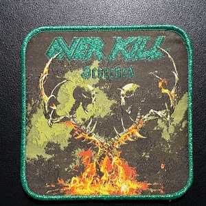 Könnte beinhalten: Quadratischer Aufnäher mit grünem, genähtem Rand. Der Aufnäher zeigt den Text "OVER KILL" und "Scorched" in Grün. Das Design zeigt zwei Skelettfiguren mit Flammen und einem grün-braunen Hintergrund.