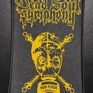 Può includere: Toppa rettangolare nera con ricamo giallo. Il testo "Dead Soul Symphony" è sopra un disegno di maschera antigas con ossa incrociate. Le parole "Mind Plague" sono ricamate sotto in giallo.