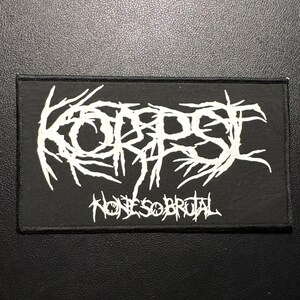Op de afbeelding: Zwart rechthoekig embleem met de witte tekst "KORPSE" in een gestileerd lettertype boven "NONE SOBROTAL". De patch is bedoeld voor kleding of accessoires, met een gotische of metalen esthetiek.