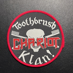 Könnte beinhalten: Runder, schwarzer Aufnäher mit rotem Rand. Der Aufnäher zeigt den Text "Toothbrush Chariot Klan!" in Weiß und Rot, mit einem Totenkopf und gekreuzten Zahnbürsten.