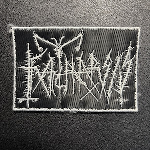 Könnte beinhalten: Schwarzer rechteckiger Aufnäher mit weiß gesticktem Text und abstraktem Design. Der Aufnäher hat ein detailliertes, kompliziertes Design mit weißem Rand. Der Text ist stilisiert und scheint ein Bandlogo oder -emblem zu sein.