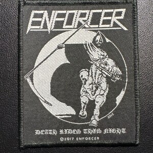 Könnte beinhalten: Schwarzer quadratischer Aufnäher mit weißem gesticktem Design. Das Wort "ENFORCER" steht oben. Darunter eine weiße Illustration eines Sensenmanns auf einem Pferd. Der Text "DEATH RIDES THIS NIGHT" und "©2017 ENFORCER" stehen unten.