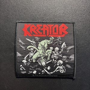 Może przedstawiać: Czarna kwadratowa naszywka z czerwonym napisem "KREATOR". Naszywka przedstawia grafikę szkieletów i zielonego potwora. Naszywka ma czarną obwódkę i tekst "©1990 DRAKKAR PROMOTIONS" na dole.