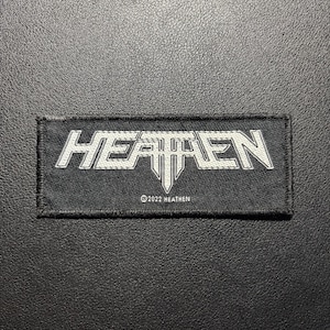 May include: A rectangular black embroidered patch featuring the word HEATHEN in a stylised white font with a sharp, pointed design element under the letter T. Below the main text, the smaller white text reads ©2022 HEATHEN with a stitched border.