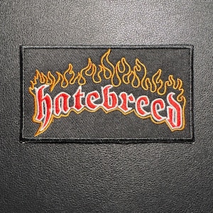 May include: A rectangular black patch with the word "hatebreed" in red, outlined in yellow, with flames above. The patch is on a textured black surface.
