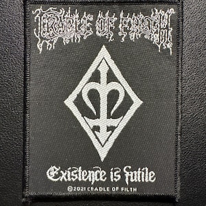 Könnte beinhalten: Schwarzer quadratischer Aufnäher mit weißem Text und einem rautenförmigen Emblem. Der Text oben lautet "CRADLE OF FILTH" in einer gotischen Schrift. Darunter steht "Existence is futile".