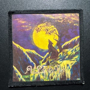 May include: Square patch with a colorful illustration of a wolf howling at a large yellow moon. The scene includes a tree, mountains, and the word "Ulver" in a stylized font. The patch has a black border.