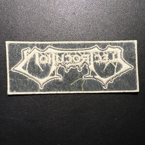 May include: A rectangular patch featuring the word "MORBID" in a gothic font. The text is white with a darker outline, set against a grey background. The patch has a white border.