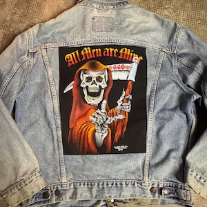 May include: Light blue denim jacket with a large patch on the back featuring a skull Grim Reaper in a red robe holding a scythe. The patch reads "All Men are Mine 666".
