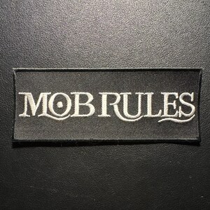 May include: A rectangular black patch with the words "MOB RULES" embroidered in white. The text is in a stylized font. The patch is likely for clothing or accessories.