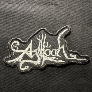 Könnte beinhalten: Schwarzer gestickter Aufnäher mit weißen Nähten. Der Aufnäher zeigt das Wort "Asblood" in einer stilisierten Schriftart, mit einem baumartigen Design, das in die Schrift integriert ist. Der Aufnäher befindet sich auf einem schwarzen Stoffhintergrund.