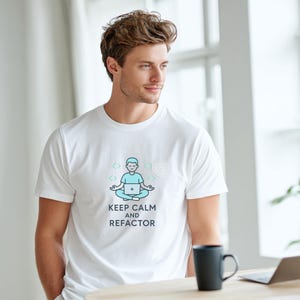 Könnte beinhalten: Weißes T-Shirt mit einer Grafik einer meditierenden Person mit Laptop, umgeben von Codesymbolen. Darunter steht der Text "KEEP CALM AND REFACTOR". Das T-Shirt wird von einer Person in einem hellen Raum getragen.