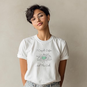 Könnte beinhalten: Weißes T-Shirt mit dem Text "7 Compile Coffee...and Then Code" in schwarzer Schrift. Das Design beinhaltet eine türkisfarbene Kaffeetasse in einer Leiterplattengrafik. Die Person trägt eine Brille und Jeans.