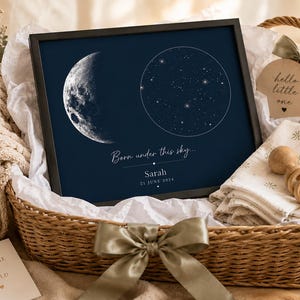 Könnte beinhalten: Ein gerahmter Druck mit dunkelblauem Hintergrund zeigt eine detaillierte Mondphase und eine Sternenkarte. Der Text lautet "Born under this sky..." mit einem Namen und einem Datum. Der Druck befindet sich in einem Weidenkorb mit Babyartikeln.