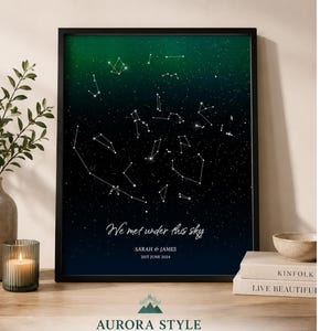 Könnte beinhalten: Gerahmter Druck mit einer Sternenkarte mit Sternbildern auf einem blau-grünen Farbverlauf. Der Text "We met under this sky" ist zu sehen, zusammen mit Namen und einem Datum. Der Druck befindet sich in einem schwarzen Rahmen, mit dem Aurora Style Logo unten.