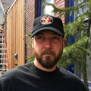 May include: A man with a beard wearing a black baseball cap with the text "National Wildlife Federation" in gold lettering.