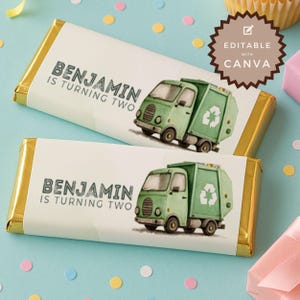 Może przedstawiać: Dwa opakowania czekolady ze złotymi końcami. Każde opakowanie zawiera napis "BENJAMIN IS TURNING TWO" i zieloną ilustrację śmieciarki. Tło jest jasnoniebieskie z konfetti i papilotką na babeczki.