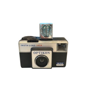 May include: A black and silver vintage camera with a built-in flash. The camera has the text "INSTA-LOAD 145X" and "OPTIKON" printed on it. The camera is labeled "126 FILM CARTRIDGE".