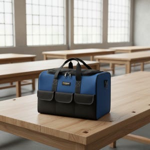 May include: A blue and black tool bag with a black top and handle sits on a wooden table. The bag has three front pockets and a silver zipper. The brand name "WINMUNT" is visible on the front of the bag.