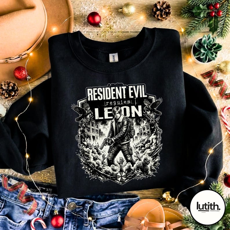 Może przedstawiać: Czarna bluza z okrągłym dekoltem z grafiką Resident Evil. Projekt zawiera tekst "Resident Evil Requiem Leon" oraz ilustrację postaci z bronią, otoczonej przez zombie i budynki w czerni i bieli.