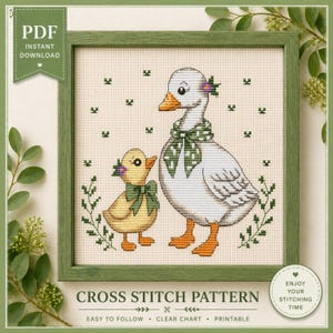 Puede incluir: Un patrón de punto de cruz con una oca y un patito, ambos adornados con lazos verdes y detalles florales. El diseño está enmarcado en un marco de madera verde. El texto incluye "PDF Descarga instantánea" y "Patrón de punto de cruz".