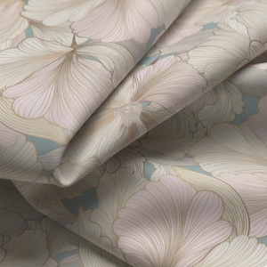 Op de afbeelding: Close-up van een stof met een bloemenpatroon. Het ontwerp toont grote, gestileerde bloemen in tinten beige, roze en lichtblauw. De stof is gevouwen, waardoor het gelaagde patroon en de textuur zichtbaar zijn. De algehele esthetiek is zacht en elegant.
