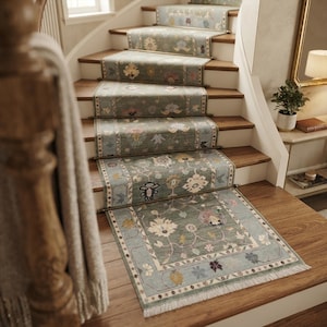 May include: A sage green stair runner rug featuring a repeating floral pattern in muted tones of blue, cream, and pink. The runner is secured to wooden stairs with metallic rods and finished with a short white fringe at the bottom edge.
