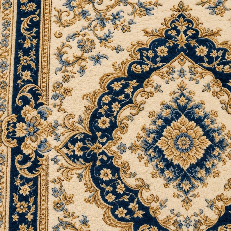 May include: A woven area rug featuring a cream-colored background with intricate floral and medallion patterns in deep blue and golden tan. The design includes a wide border with repeating floral motifs and a central diamond-shaped medallion.