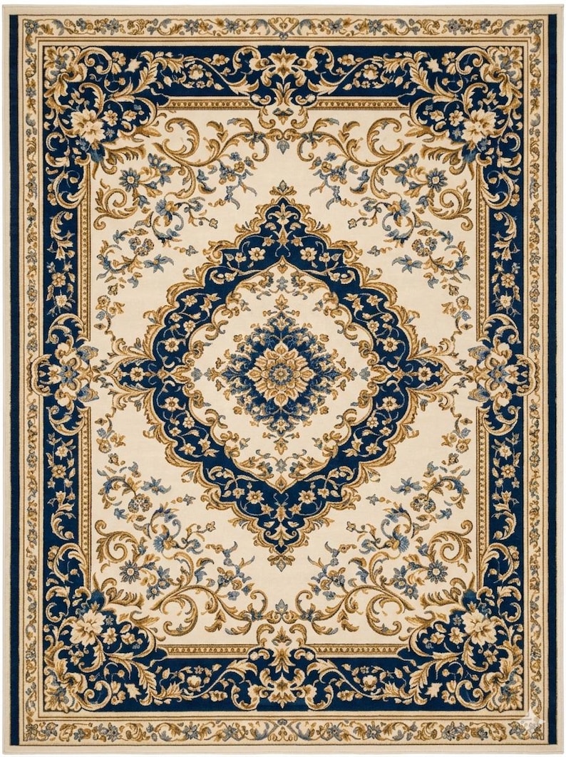May include: A rectangular area rug featuring a cream-colored center with a large, intricate navy blue and gold floral medallion. The border consists of a wide navy blue frame adorned with scrolling gold vines, flowers, and cream-colored accents.