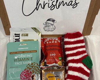 May include: A Christmas gift box filled with festive items. Includes a face mask, popcorn, eye masks, candy canes, Santa Claus-themed decorations, and a red and white striped sock. The box lid has "Merry Christmas" written on it.