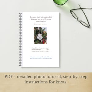 May include: A spiral-bound book with the title "Macrame - basic informations, first knots and easy to do Christmas pennant pattern." The book includes a photo tutorial and step-by-step instructions for knots. A pair of glasses and a green glass are also visible.