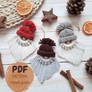 May include: Three handmade gnome ornaments with knitted hats in red, brown, and gray, each with a white or gray beard. The ornaments are made of yarn and wood, and are hanging. The image also includes dried orange slices, a star, and pine cones.