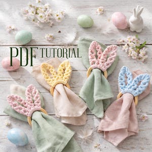 May include: Easter-themed table setting with four linen napkins, each adorned with a crochet bunny ear napkin ring in pastel colors: yellow, pink, and blue. The image includes decorative eggs, flowers, and the text "PDF TUTORIAL".