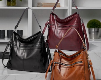 May include: Three leather shoulder bags in black, burgundy, and brown. Each bag has multiple zippered compartments and adjustable straps. The bags are displayed on a white surface.