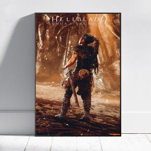 Puede incluir: Un póster enmarcado del juego "Hellblade: Senua's Sacrifice". La obra de arte muestra un personaje con ropa oscura, sosteniendo una espada, sobre un fondo rocoso en tonos sepia. El título del juego se muestra en la parte superior.