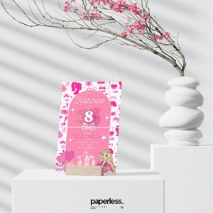 May include: A pink birthday invitation with the name "Katherine" and the number "8" in the center. The invitation features a Barbie-themed design with illustrations of accessories and a Barbie character. The invitation is displayed on a wooden stand.