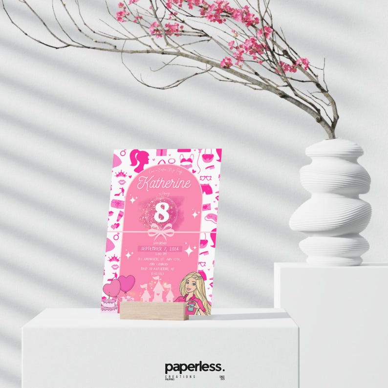 May include: A pink birthday invitation with the name "Katherine" and the number "8" in the center. The invitation features a Barbie-themed design with illustrations of accessories and a Barbie character. The invitation is displayed on a wooden stand.