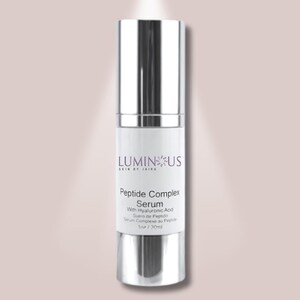 Puede incluir: Una botella plateada y blanca de suero LUMINUS Peptide Complex. La botella tiene una tapa y base metálicas, con una etiqueta blanca con el nombre de la marca y los detalles del producto. También incluye el texto "With Hyaluronic Acid".