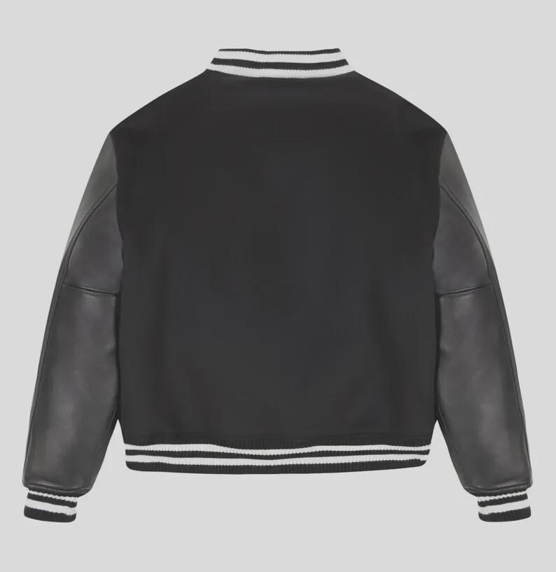 Op de afbeelding: Een zwart varsity-jack met lange mouwen met een gladde textuur, een geribbelde kraag, boorden en zoom met witte strepen. Het jack heeft een effen zwart lichaam en bijpassende zwarte mouwen, wat zorgt voor een klassiek en sportief ontwerp.
