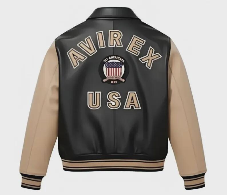 Puede incluir: Una chaqueta tipo varsity negra y beige con el texto AVIREX y USA en letras beige en la espalda. Un parche circular con un gr&aacute;fico de la bandera estadounidense y el texto OLD AMERICAN 1975 est&aacute; centrado entre las palabras. La chaqueta tiene cuello y pu&ntilde;os.
